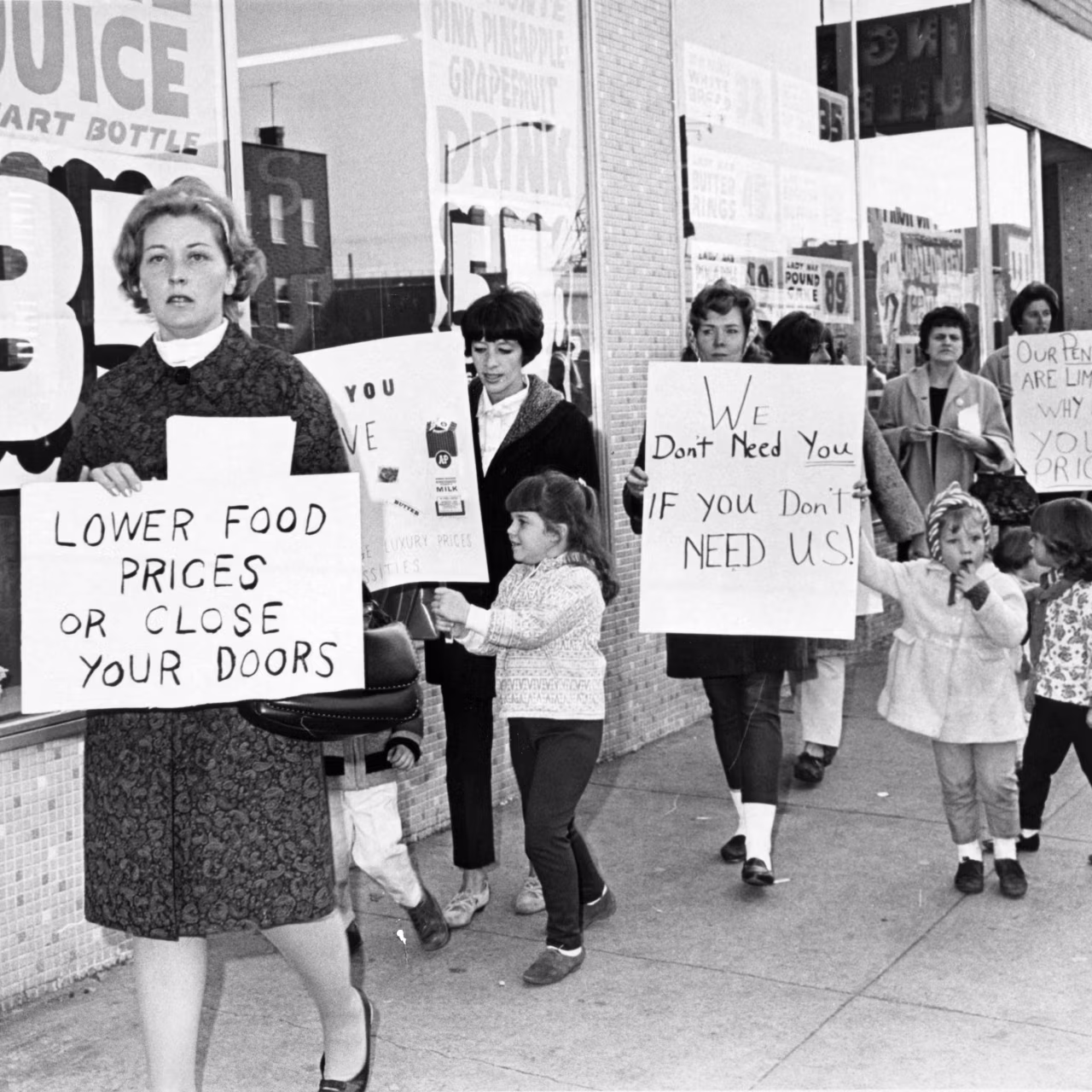 Women carrying protest banners in a picket line of a grocery store in the 1960's.